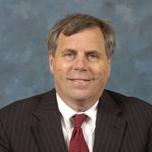 White man in black suit and red tie