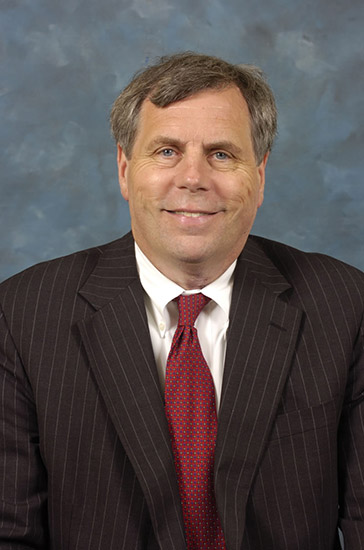 White man in black suit and red tie