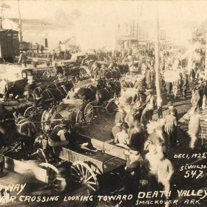 Crowd of white men with horse drawn wagons at rail yard