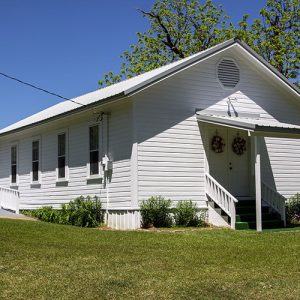 Single-story building with white siding and covered front entrance with covered back entrance and wheelchair ramp on its left side