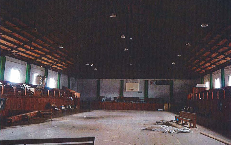 Basketball court with hoop and bleachers inside gymnasium