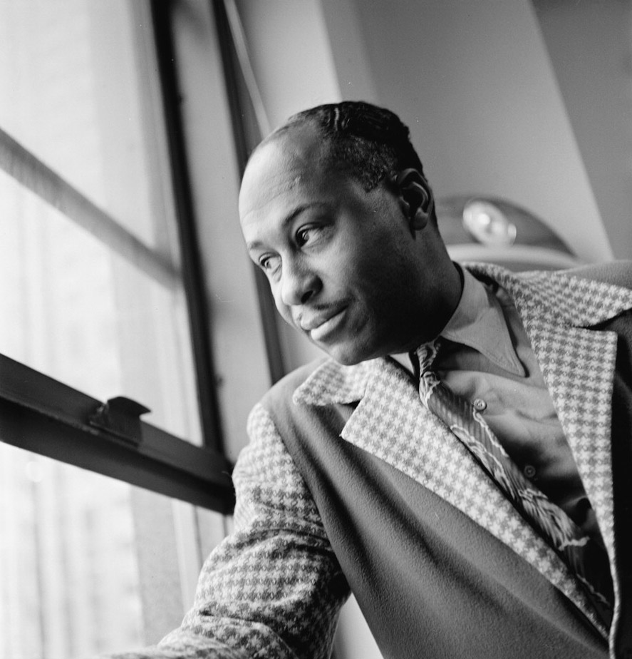 African-American man in plaid suit jacket and tie looking out a window