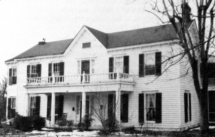 Two-story white house with covered porch and balcony above it