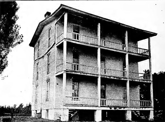 Three-story building with covered porch and balconies on each floor