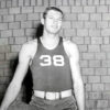 Young man with basketball in number "38" uniform standing at brick wall
