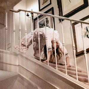 White woman bent over backwards "walking" down a flight of stairs on film set