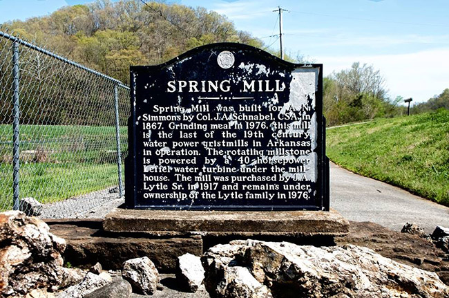 Weathered "Spring Mill" historical marker sign on stone platform