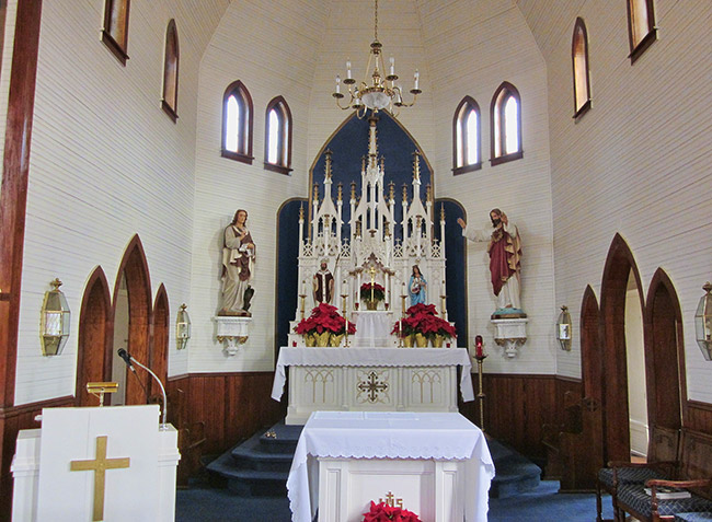 High altar under chandelier in sanctuary room with gothic arched windows and doorways