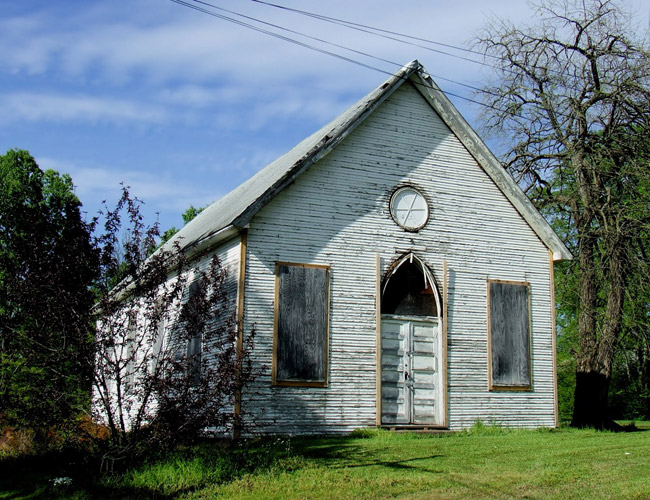 Single-story church with arched entrance in state of dilapidation