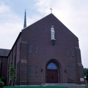 Brick church building with raised statue on wall and arched entrance