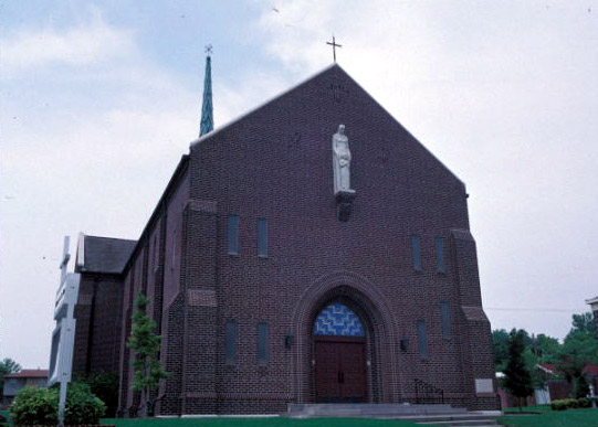 Brick church building with raised statue on wall and arched entrance