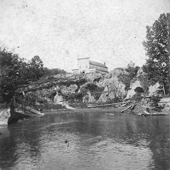 Multistory building on rock bluff overlooking river in the foreground