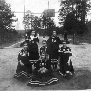 Group of young white girls in matching uniforms on outdoor basketball court
