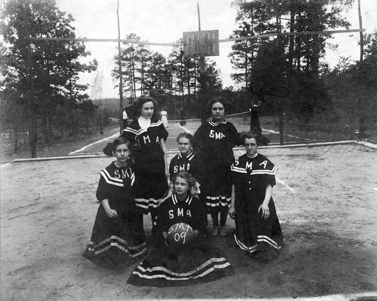 Group of young white girls in matching uniforms on outdoor basketball court