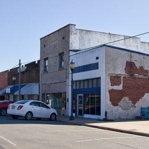 Brick storefronts on street with parked cars in front of them