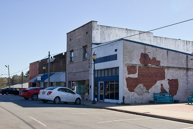 Brick storefronts on street with parked cars in front of them