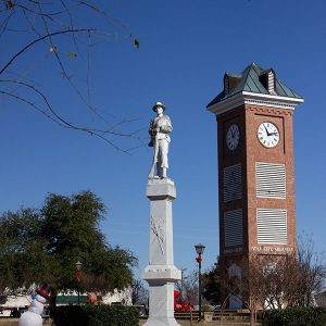 Large monument surmounted by soldier, beside clock tower