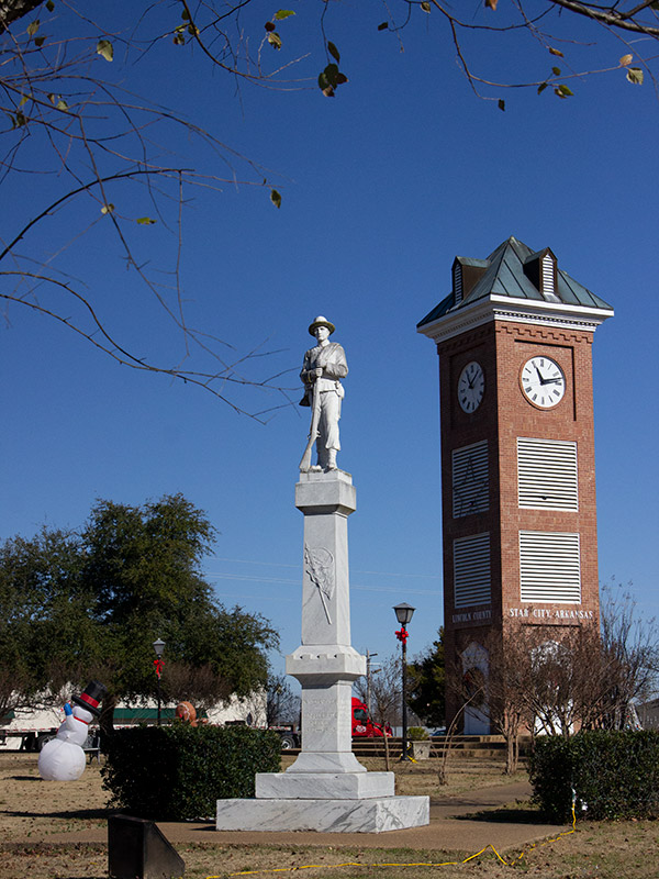 Large monument surmounted by soldier, beside clock tower