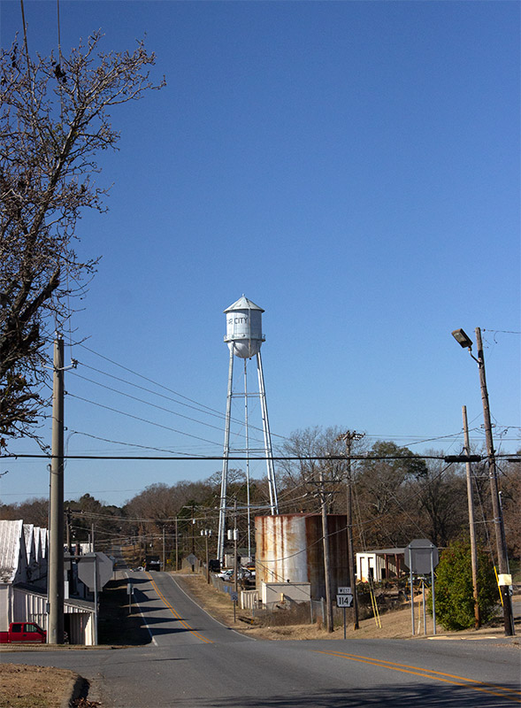 Water tower beside street with traffic