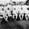 Group of white men in matching uniforms posing in naval ship