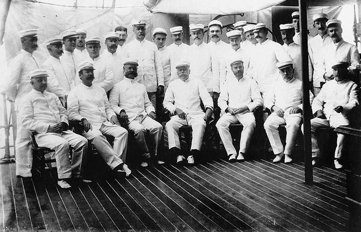 Group of white men in matching uniforms posing in naval ship