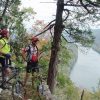 Two white men wearing helmets standing beside bicycles at cliff looking over a river below them