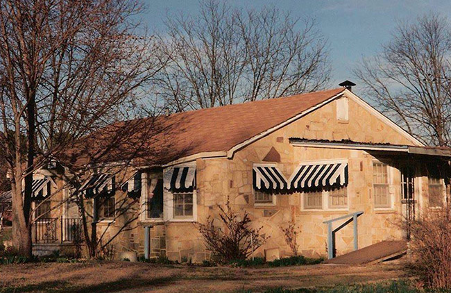 Single-story inn with striped awnings and wheelchair ramp on the back porch