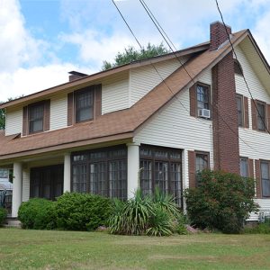 Two-story house with covered porch and brick chimney on grass