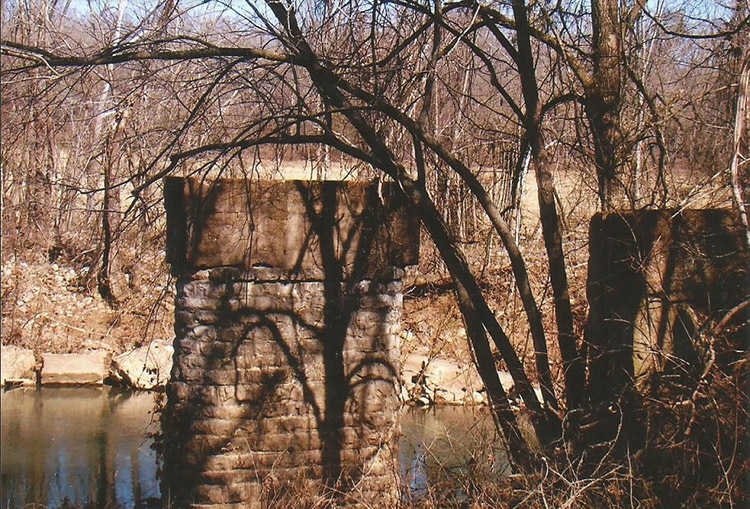 Stone bridge support columns in river in forested area