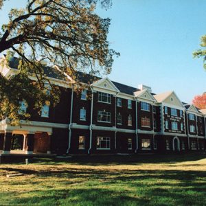 Three-story brick residence hall building on grass with trees