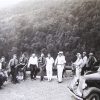 Group of white men and car at scenic overlook with tree covered mountain behind them