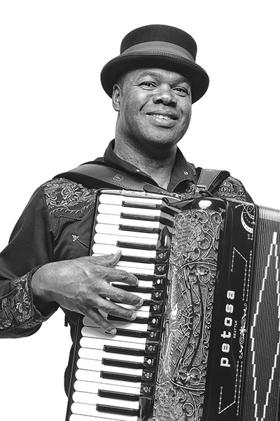 African-American man in long sleeve shirt and hat playing an accordion
