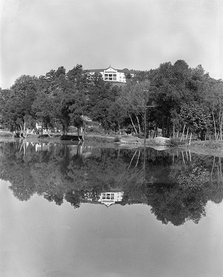 Multistory building and tree covered hill reflected in lake