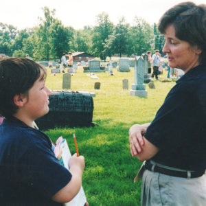 White woman speaking with children in cemetery