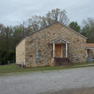 Stone church building on gravel parking lot