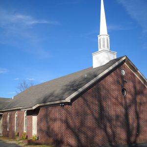 Brick church building with steeple and cross on its roof