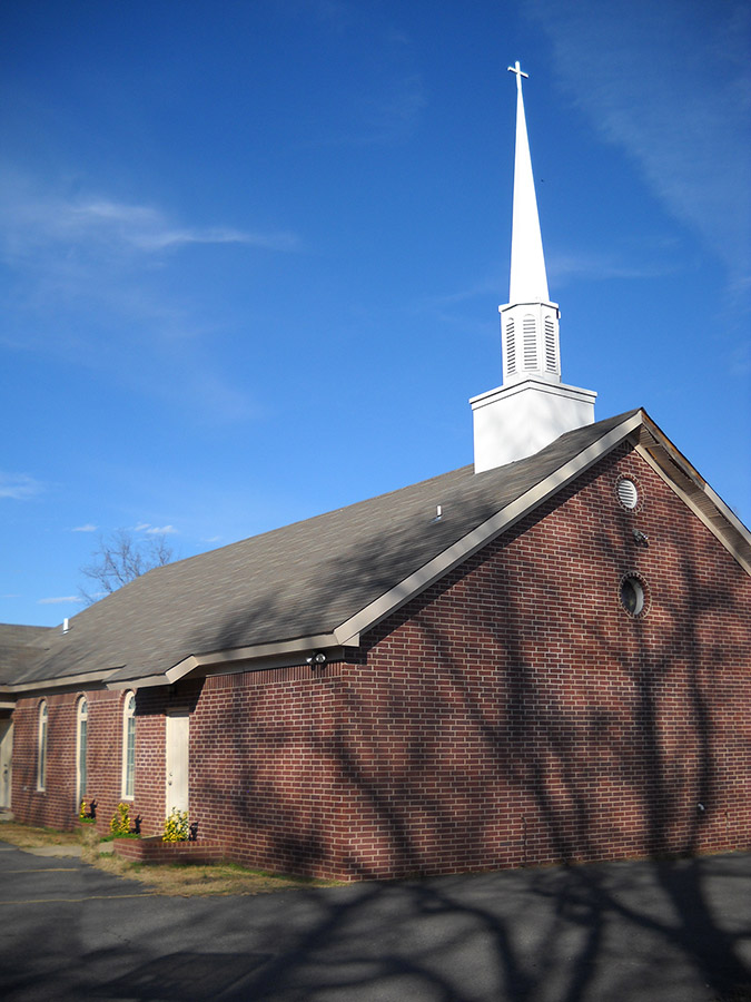 Brick church building with steeple and cross on its roof