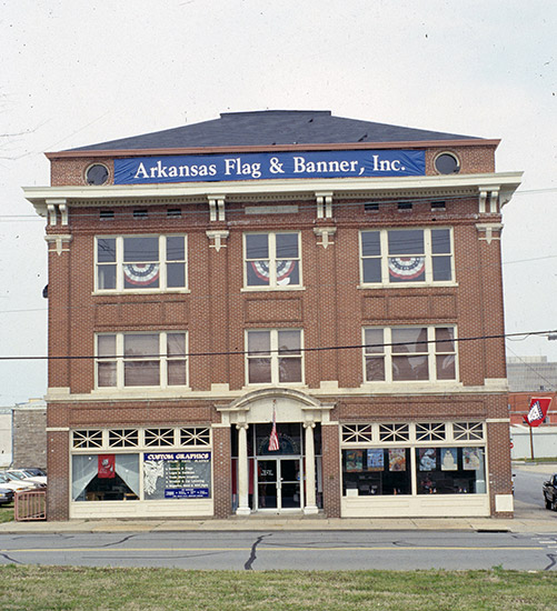front view of three-story building with a banner reading "Arkansas Flag and Banner, Inc." across the top