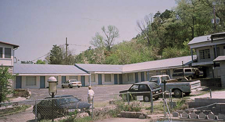 Blue and white motel building with cars in parking lot
