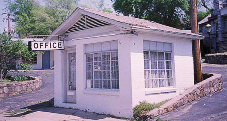 Motel building with window in front and hanging sign saying "office"