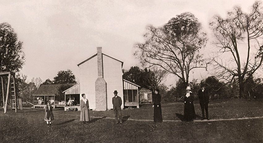 White family in yard with house and bell tower with ladder