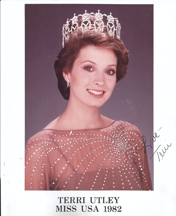 Young white woman with short hair smiling in tiara and dress with name and date below