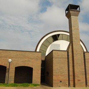 Single-story brick building with hemispherical dome chimney and arched walkway on parking lot