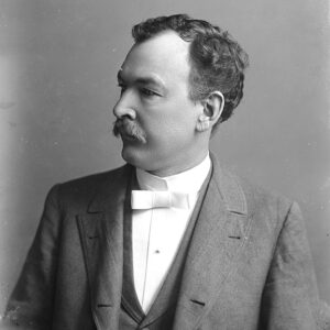 White man with mustache in suit and tie looking to the side