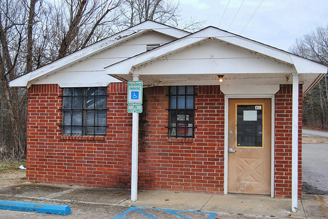 small single-story brick building with covered porch on parking lot