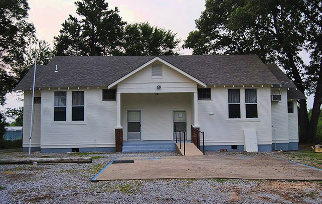 Single-story white building with covered porch and two front doors