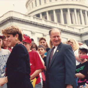 White man in suit and tie with white woman and children on Capitol building steps