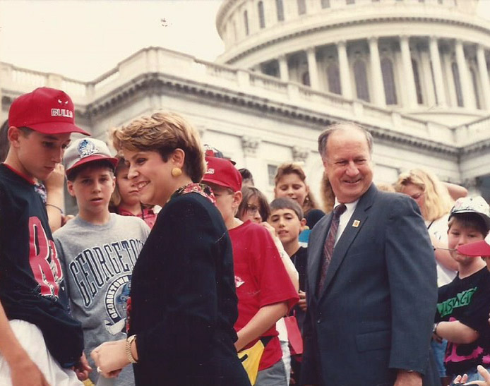 White man in suit and tie with white woman and children on Capitol building steps