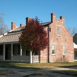 Brick house with covered porch and tree with red leaves