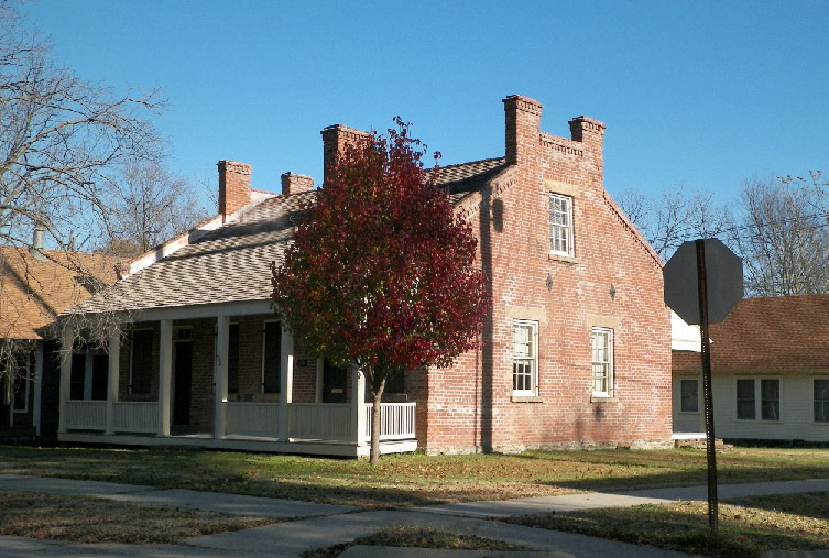 Brick house with covered porch and tree with red leaves